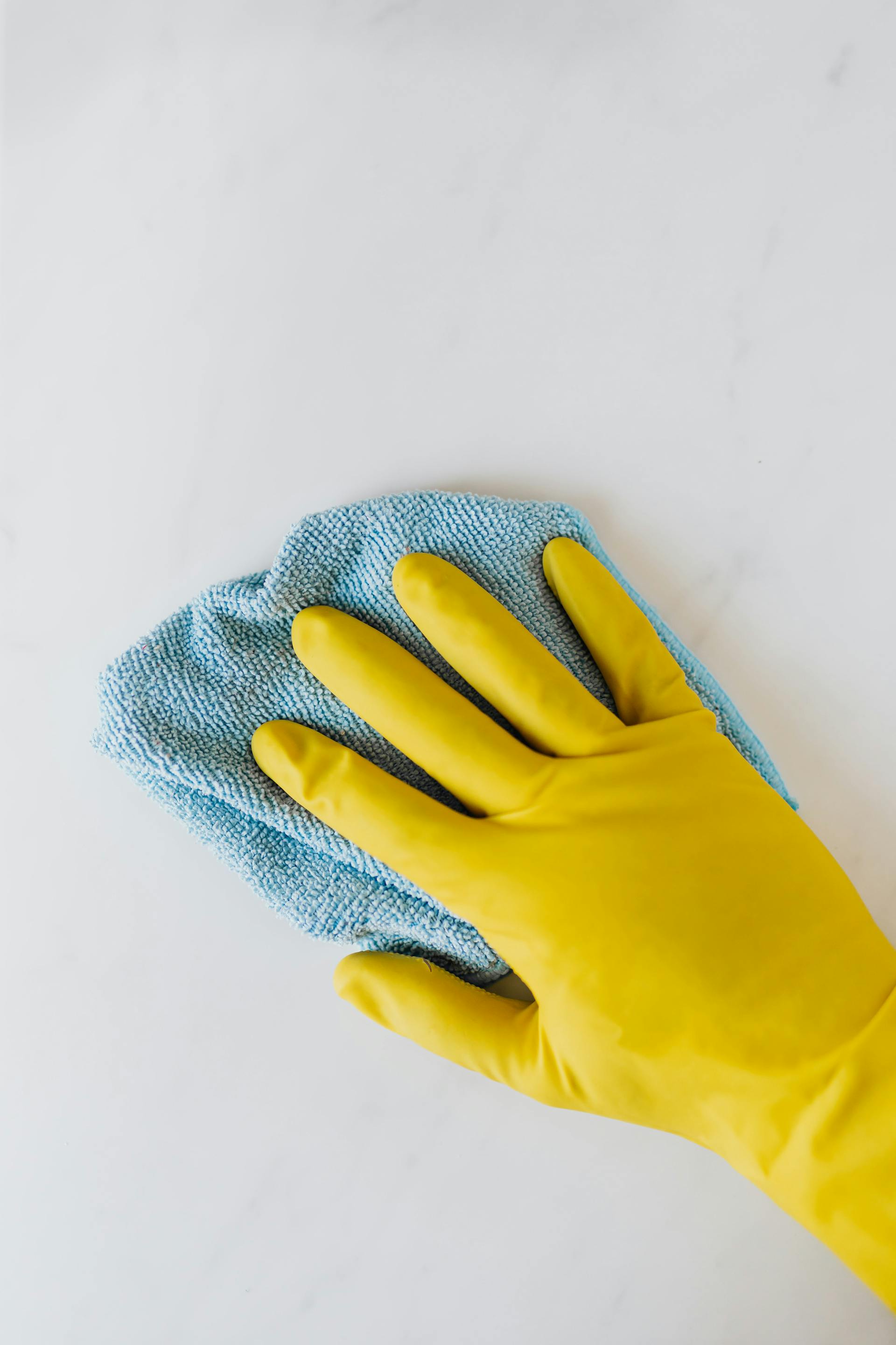 crop-unrecognizable-person-in-yellow-gloves-cleaning-white-surface