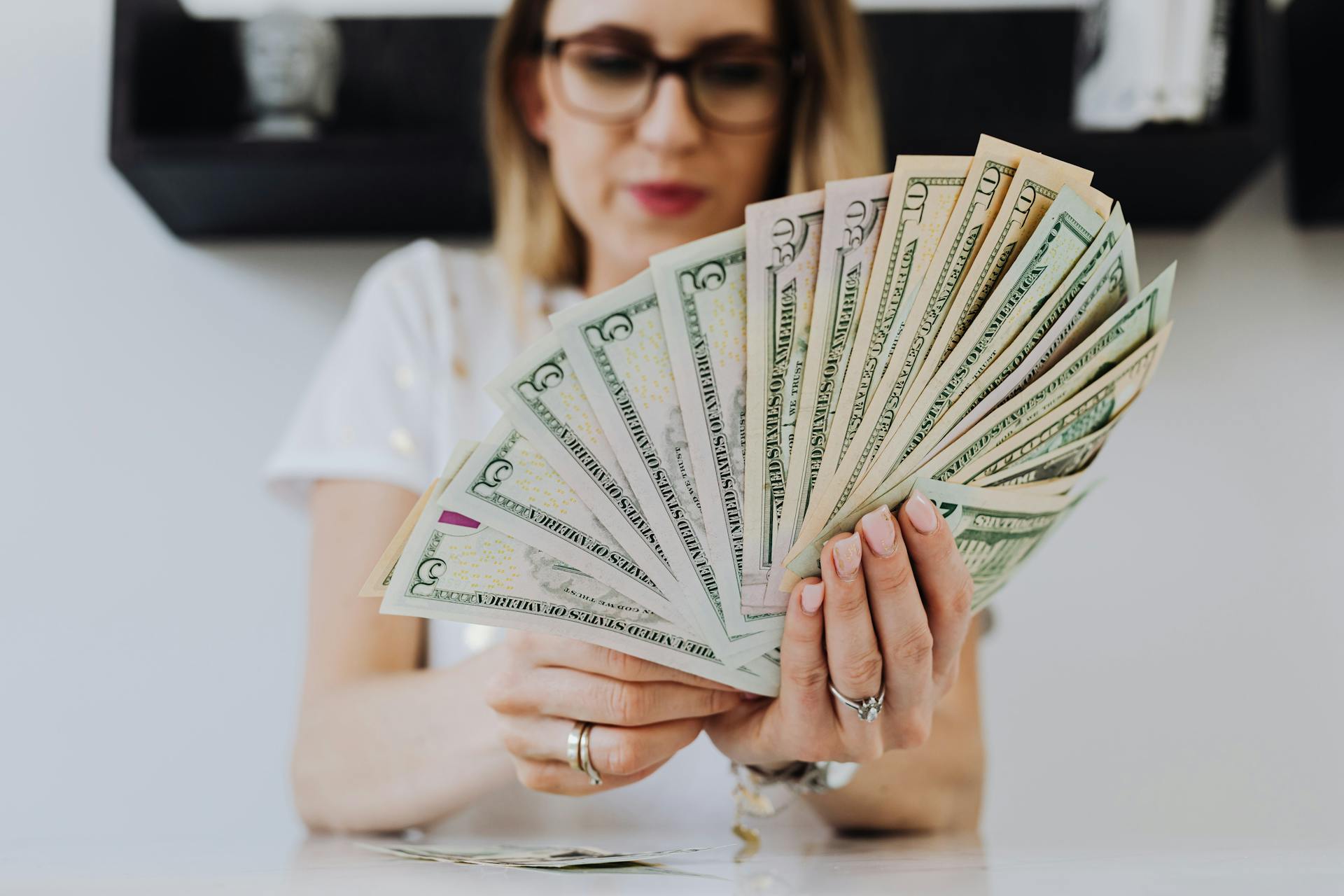 woman-holding-fan-of-us-dollar-bills