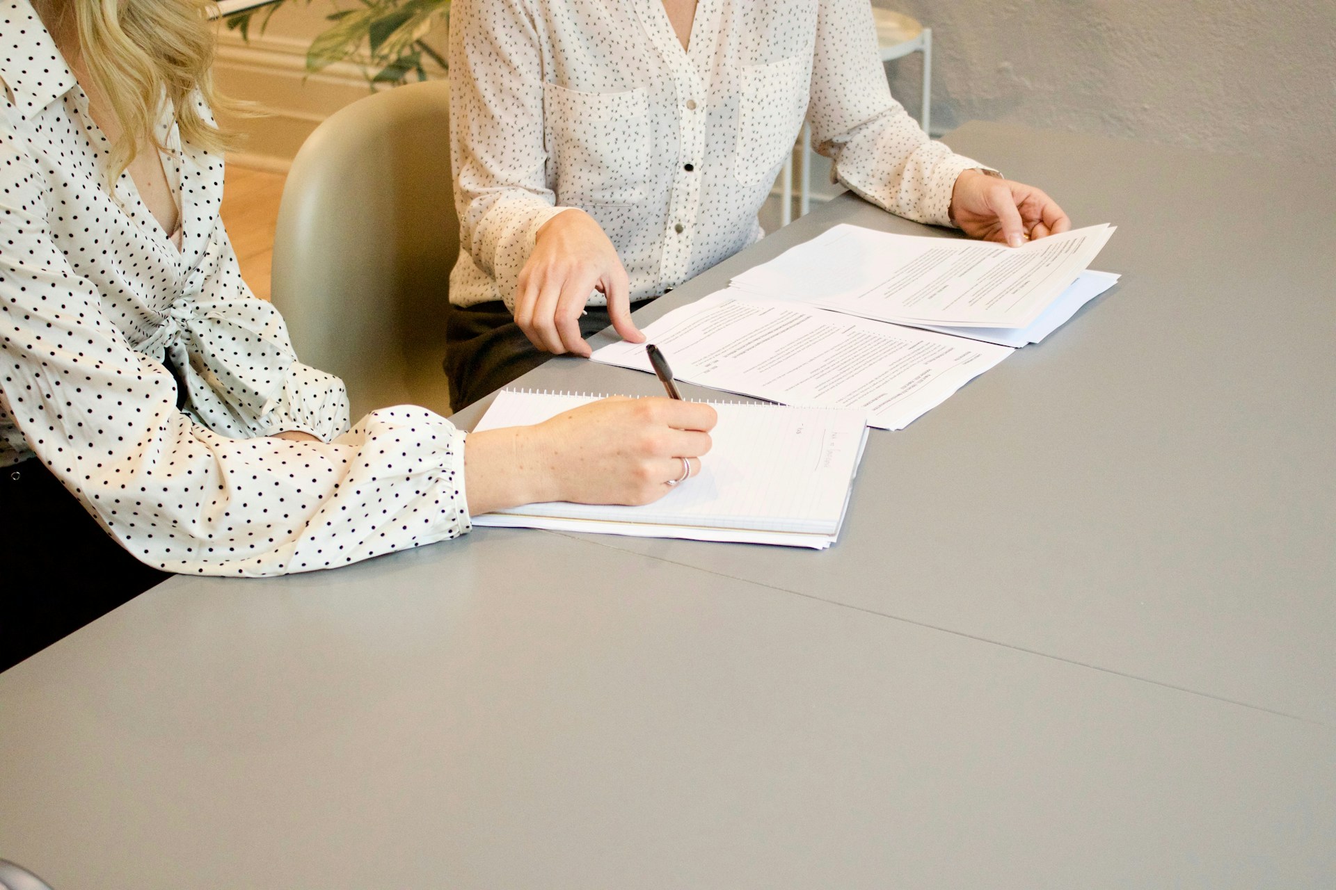 woman-signing-on-white-printer-paper-beside-woman