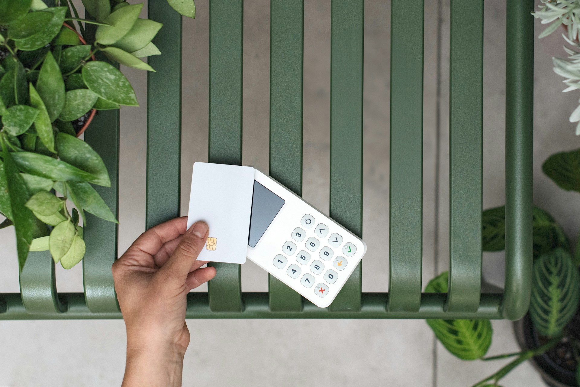 a-person-holding-a-remote-control-next-to-a-green-bench
