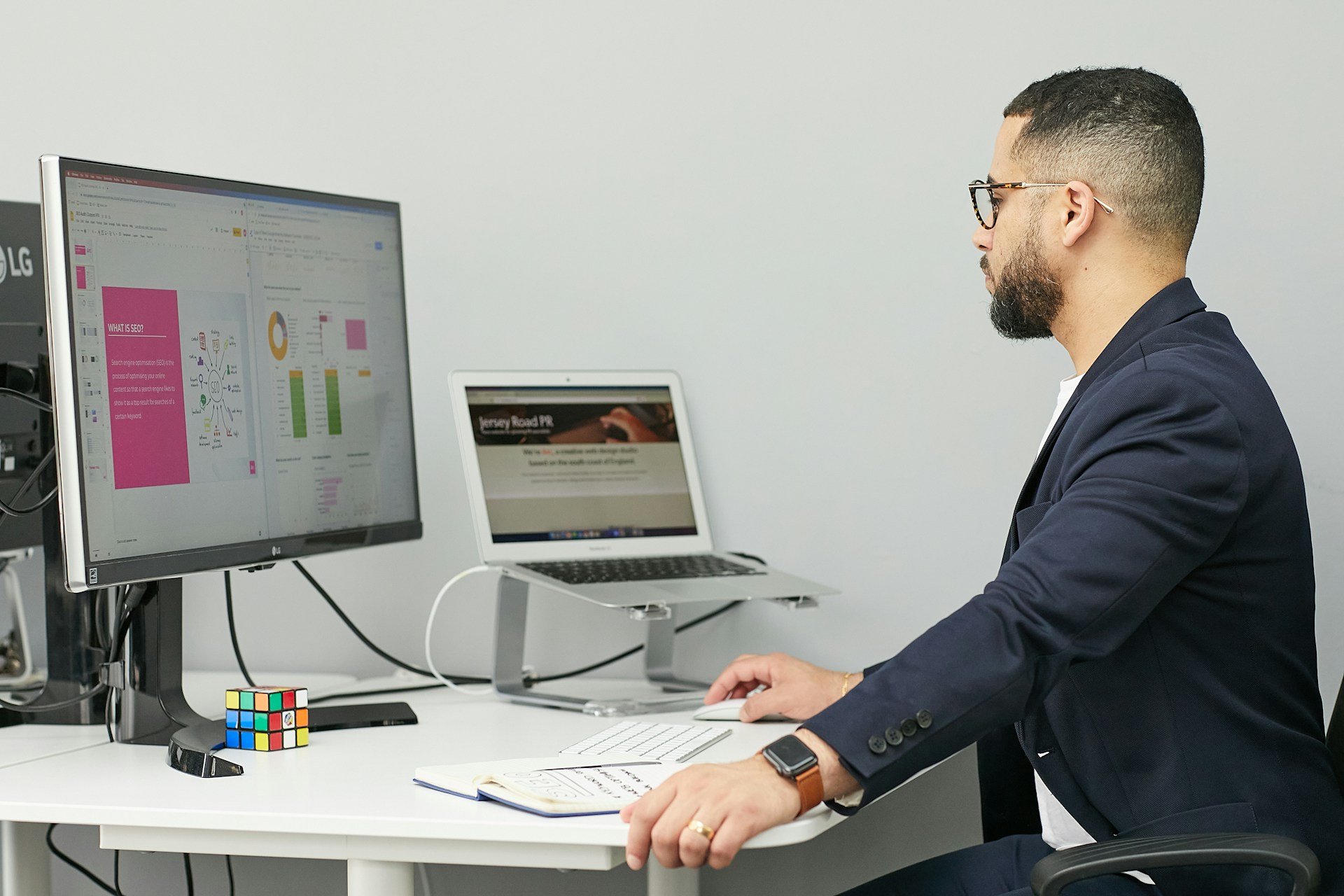 a-man-sitting-at-a-desk-with-a-laptop-and-a-computer