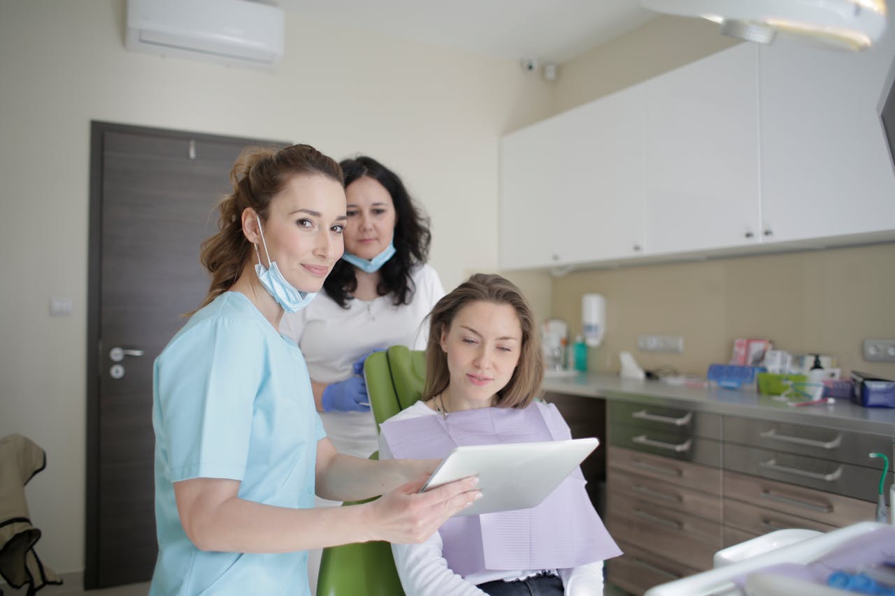 cheerful-stomatologist-and-assistant-showing-medical-report-to-patient